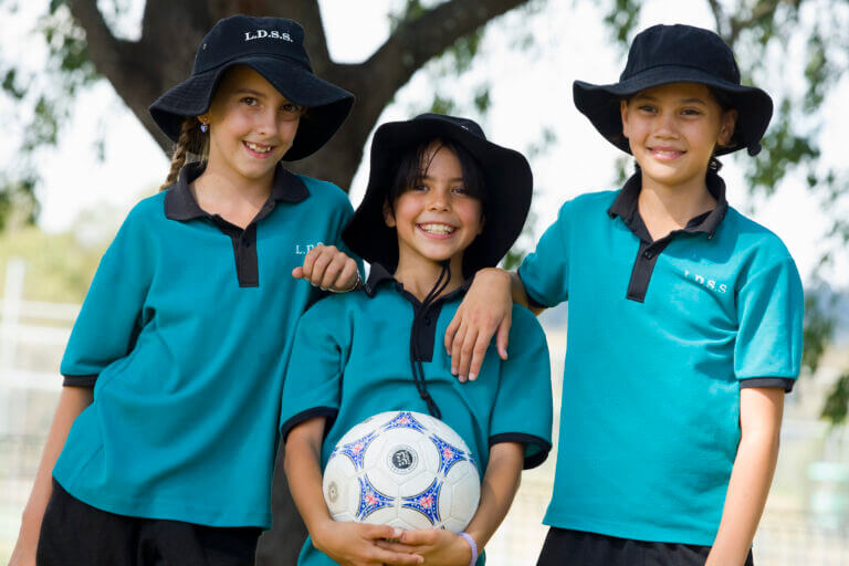 3 primary school children holding a soccer ball